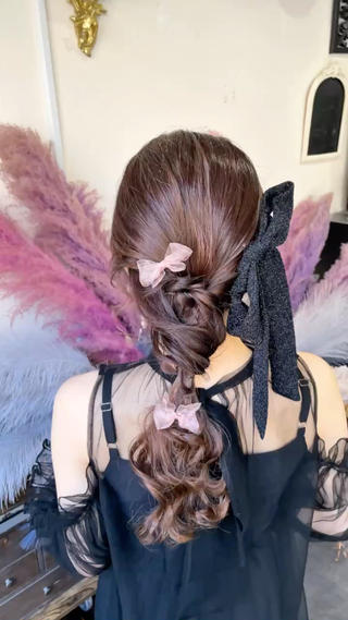 編み込みを効かせたローポニーアレンジ。やわらかなウェーブと透け感のあるリボンで、甘さと大人っぽさを両立。後ろ姿まで抜かりなく、結婚式やお呼ばれにおすすめです。 