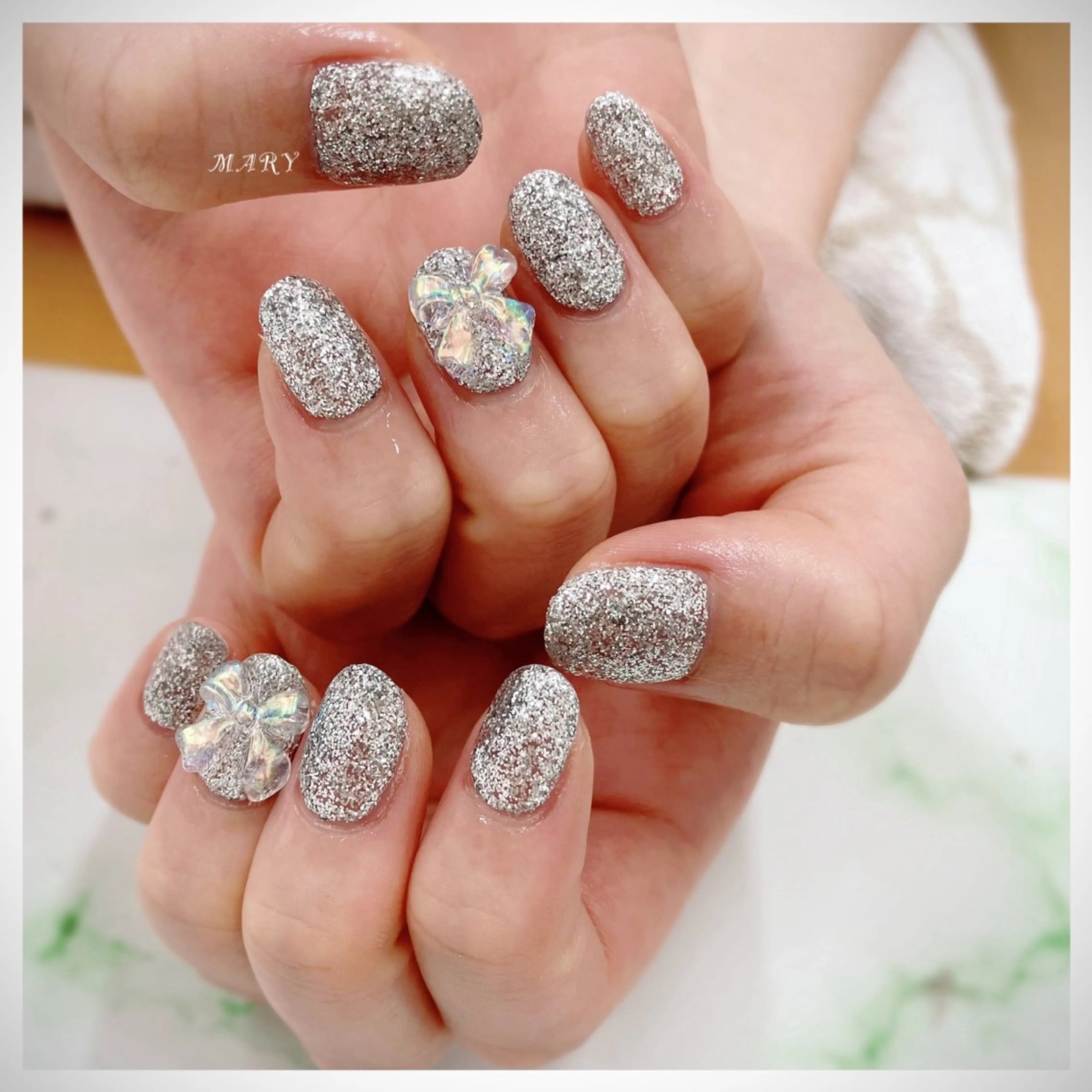 ネイル キラキラネイル ニュアンスネイル ワンカラーネイル リボン シルバー ハンドネイル Mary nail所属・Mary nail .narumiのネイルデザイン
