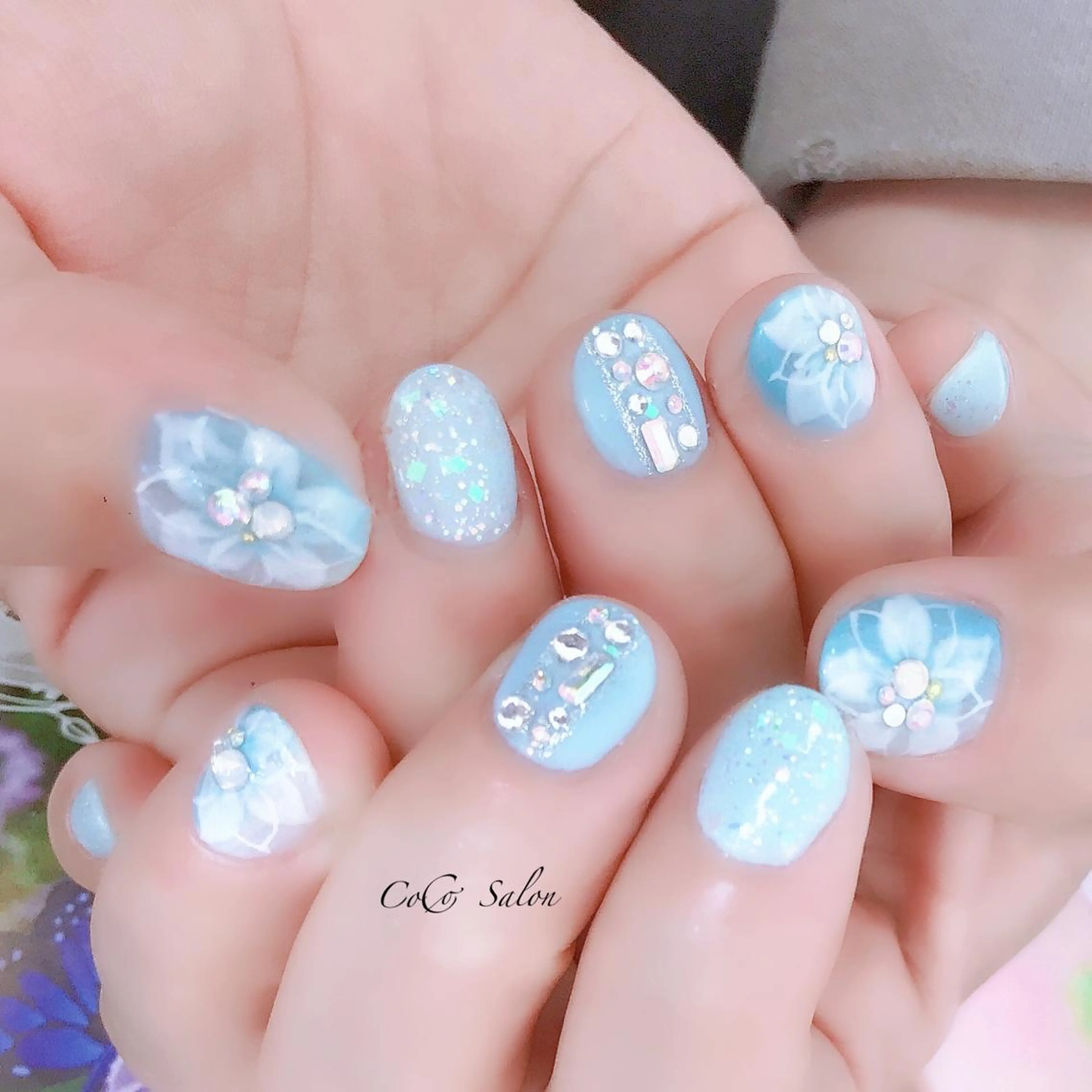 ネイル フラワーネイル キラキラネイル 水色 ショートネイル 春ネイル CoCoSalon ネイル/まつ毛予約のネイルデザイン