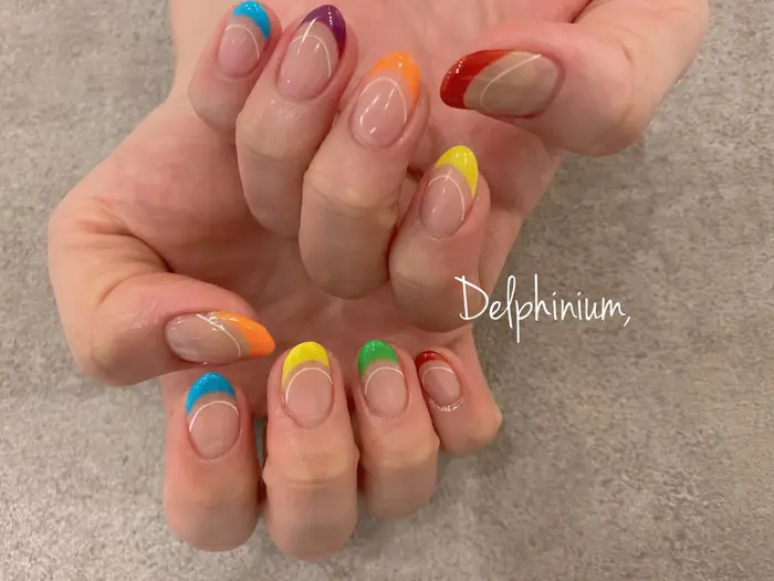 Colorfulなビビットカラーフレンチ 当店では複数メーカーのベースジェルを用意しており ネイル空間内 Delphinium所属 岡本 友恵のネイル デザイン ミニモ